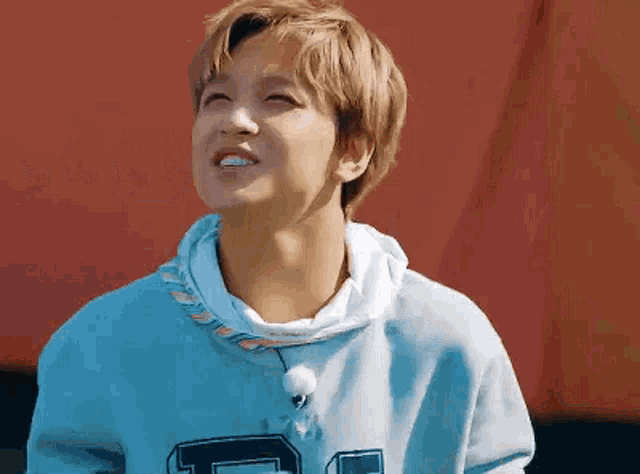 a young man in a blue hoodie is smiling and looking up .