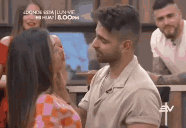 a man and a woman are kissing in front of a sign that says " donde esta " on it