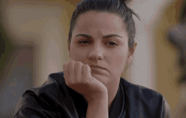 a woman with her hand on her chin is wearing earrings