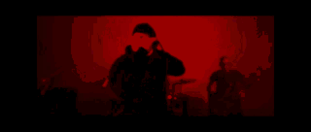 a blurred image of a person playing a guitar in front of a colorful screen