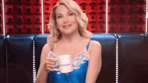 a woman is sitting on a couch holding a mug that says ' caffe ' on it .