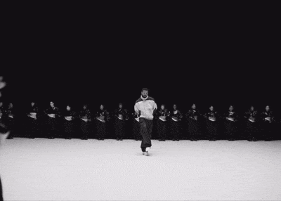 a black and white photo of a man dancing in front of a crowd