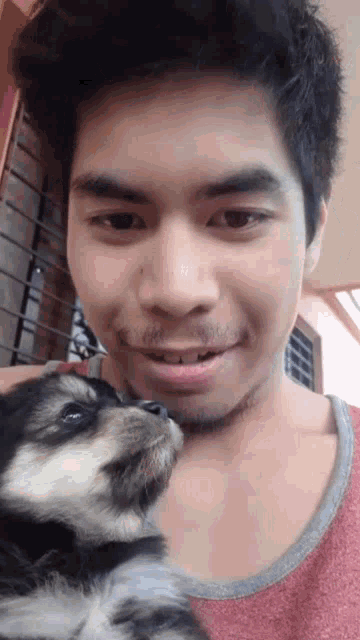 a man is holding a small black and white dog on his shoulder .