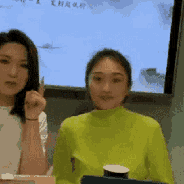 two women are sitting in front of a screen with chinese writing
