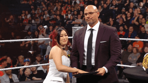 a man in a suit stands next to a woman in a wedding dress