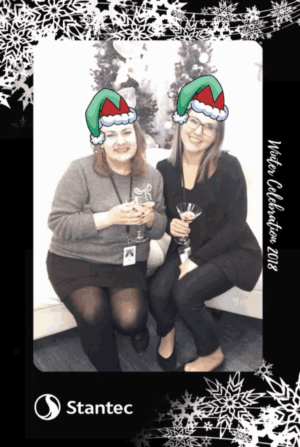 two women wearing santa hats pose for a photo with the year 2018