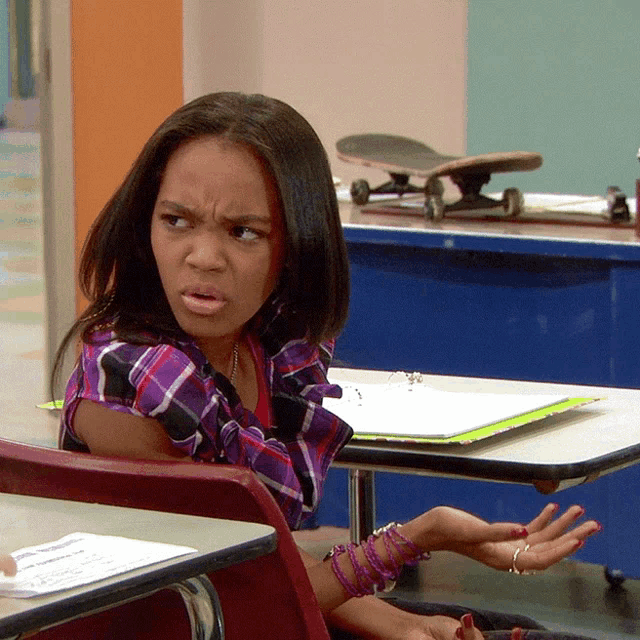a girl in a plaid shirt sits at a desk