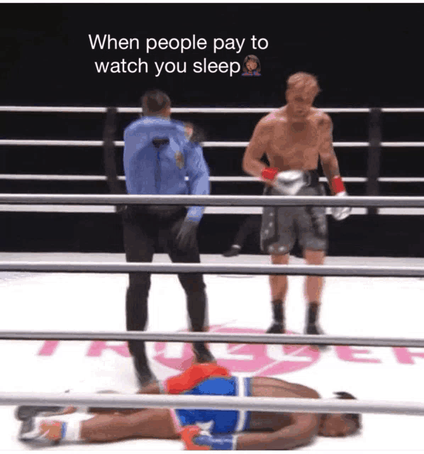 a boxer is laying on the ground in a boxing ring while a referee stands behind him