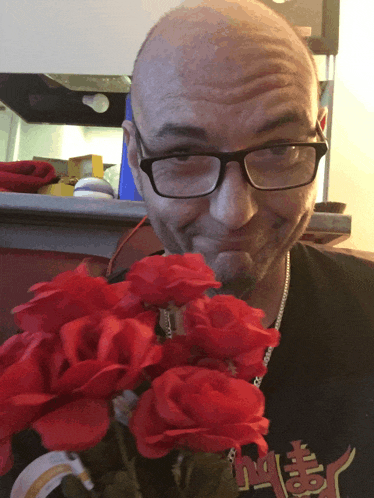 a man wearing glasses is holding a bouquet of red roses in front of him