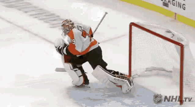 a hockey goalie is making a save on a goal during a game .