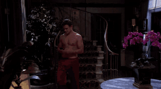 a man without a shirt is standing in front of stairs