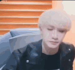 a young man with blonde hair is wearing a black leather jacket and a black shirt .