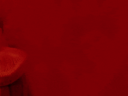a woman in a red dress is standing in front of a red background .