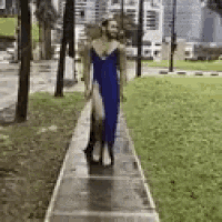 a man is walking down a sidewalk in a blue dress .