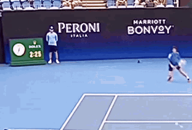 a man is playing tennis on a court with a peroni sign behind him