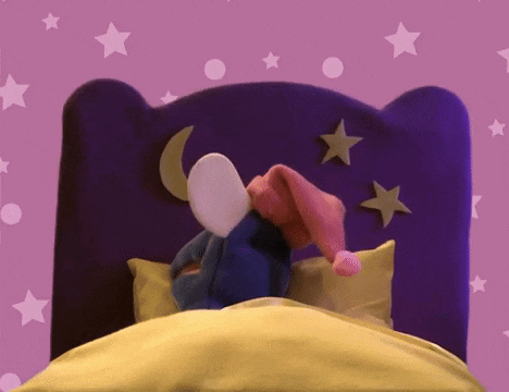 a stuffed animal is laying in a bed with a purple headboard