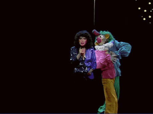 a clown is holding a woman in a pink shirt
