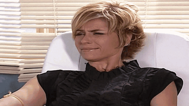 a woman in a black shirt is sitting in a chair with her eyes closed