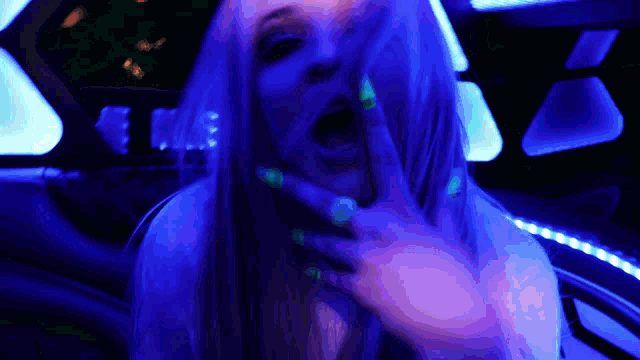 a woman with glow in the dark nails covering her face with her hand