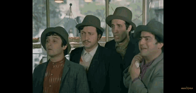 a group of men wearing hats are standing in front of a window