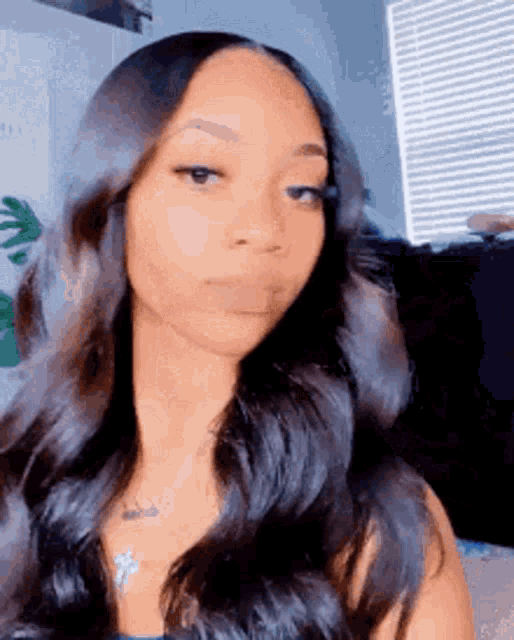 a woman with long black hair is making a funny face .