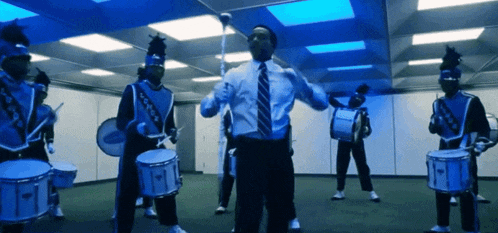 a man in a suit and tie is standing in front of a drum set
