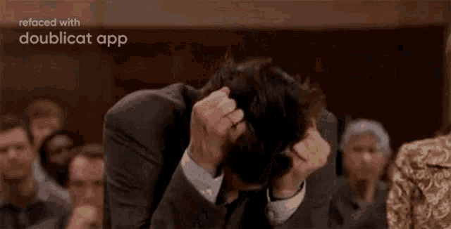 a man in a suit and tie is holding his head in his hands .
