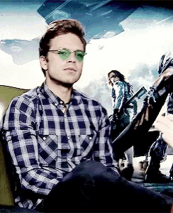 a man wearing a plaid shirt and green glasses is sitting in a car