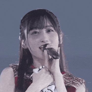 a woman is singing into a microphone with her hand on her chin
