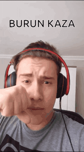 a man wearing headphones has his fist in front of his face and the words burun kaza are above him