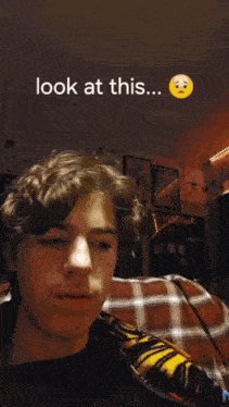 a young man sitting on a couch with the words look at this