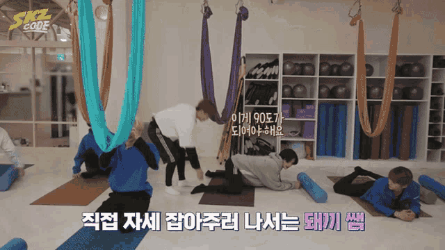 a group of people are doing yoga in a gym with a sign that says skz