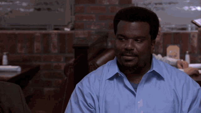 a man in a blue shirt sits at a table