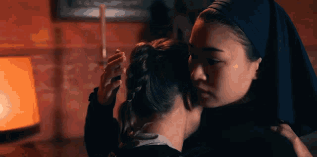 a woman in a nun 's veil is hugging another woman in a room .