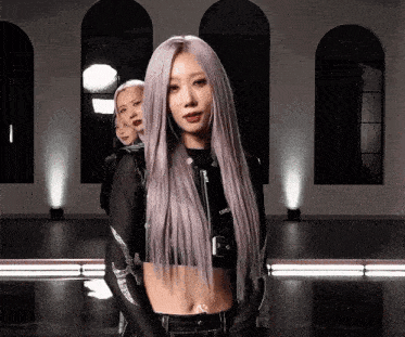 a woman with long purple hair is wearing a crop top and a black jacket .