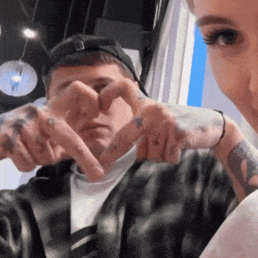 a man and a woman are making a heart with their hands