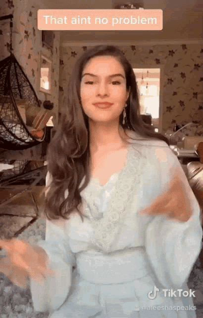 a woman in a blue dress is dancing in a living room with a caption that aint no problem