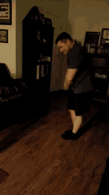 a man is jumping in a living room with a smile sign on the dresser