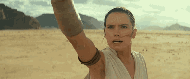 a woman in a white shirt is standing in the desert with her arm in the air