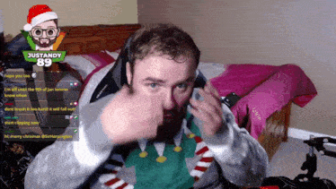 a man wearing a santa hat is sitting in front of a computer screen with justandy 89 on it