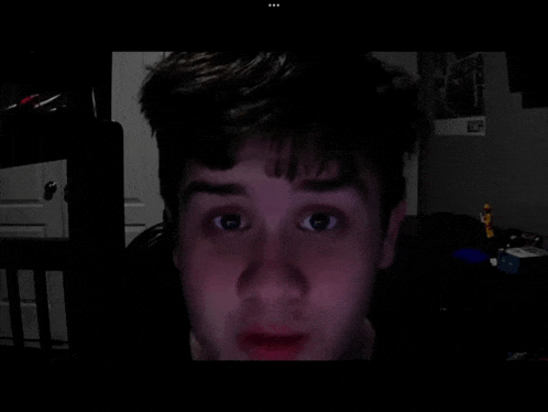 a close up of a person 's face in a dark room with a lego figure in the background