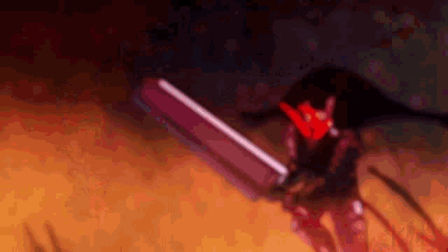 a man in a red helmet is holding a large sword in his hands .