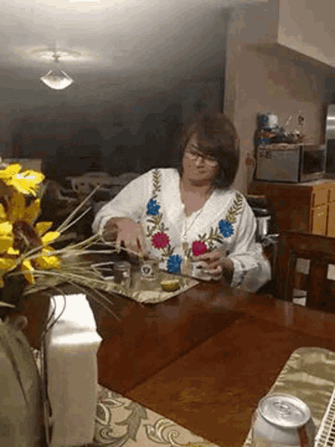a woman is sitting at a table with a can of beer on the table