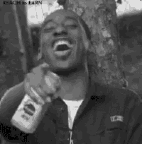 a black and white photo of a man laughing while holding a bottle of beer .