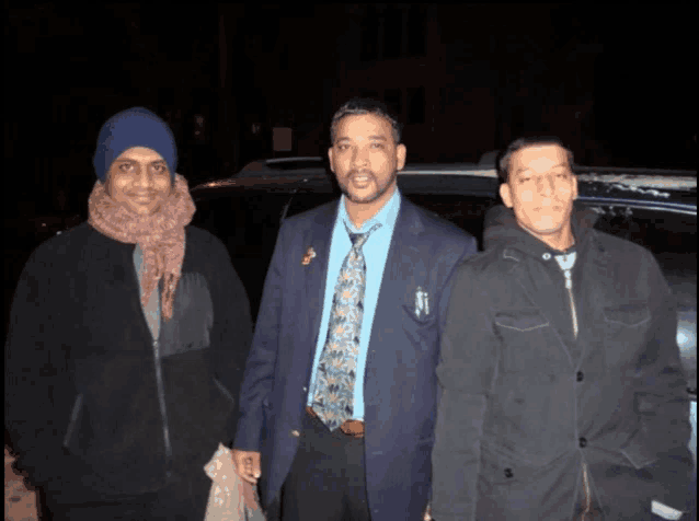 three men are posing for a picture and one of them has a pin on his jacket that says ' a '