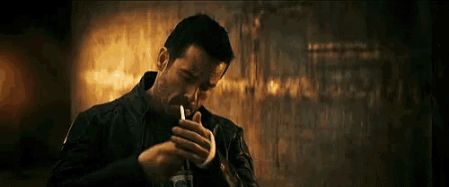 a man is smoking a cigarette in a dark room in a movie .