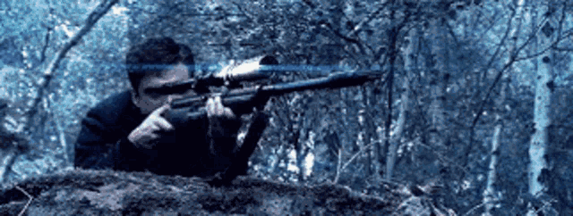 a man is holding a sniper rifle in a dark forest