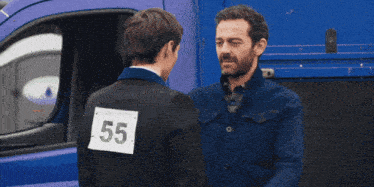 a man hugging another man with a number 55 on his jacket