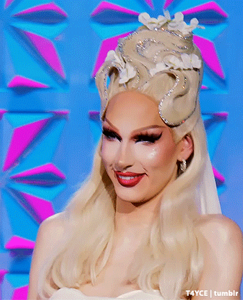 a drag queen wearing a white dress and a crown with flowers on it