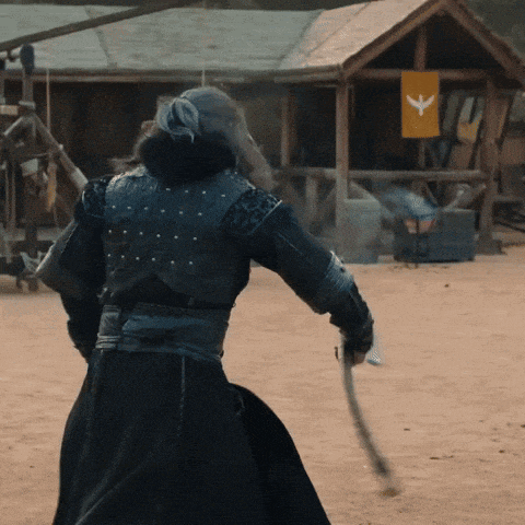 a man in armor is holding a sword in front of a small hut with a bird on it